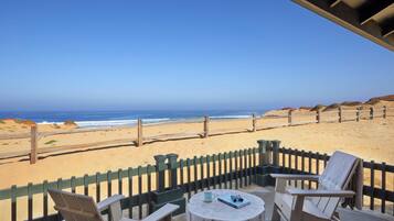 A beachside patio with two chairs and a table, overlooking the ocean.