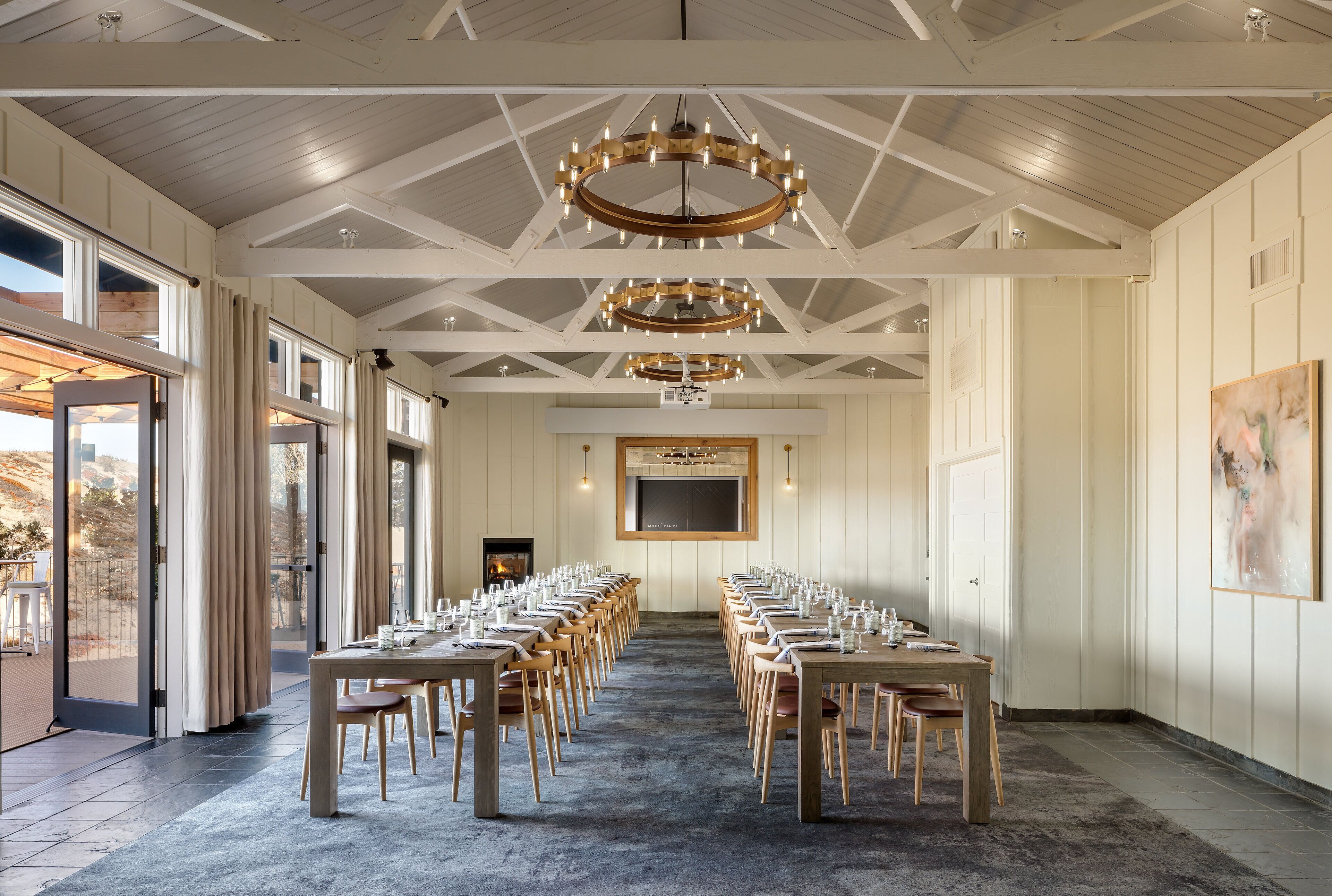 A conference room with long tables and chairs, a large screen, and a fireplace.