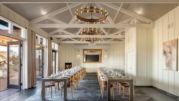 A conference room with long tables and chairs, a large screen, and a fireplace.
