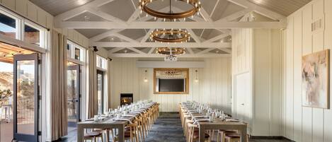 A conference room with long tables and chairs, a large screen, and a fireplace.