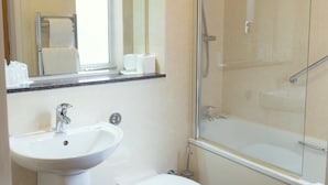 Un baño moderno con lavamanos, inodoro y ducha con mampara de vidrio.