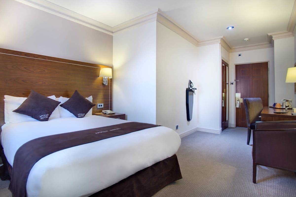 A hotel room with a large bed, a desk, and a chair.