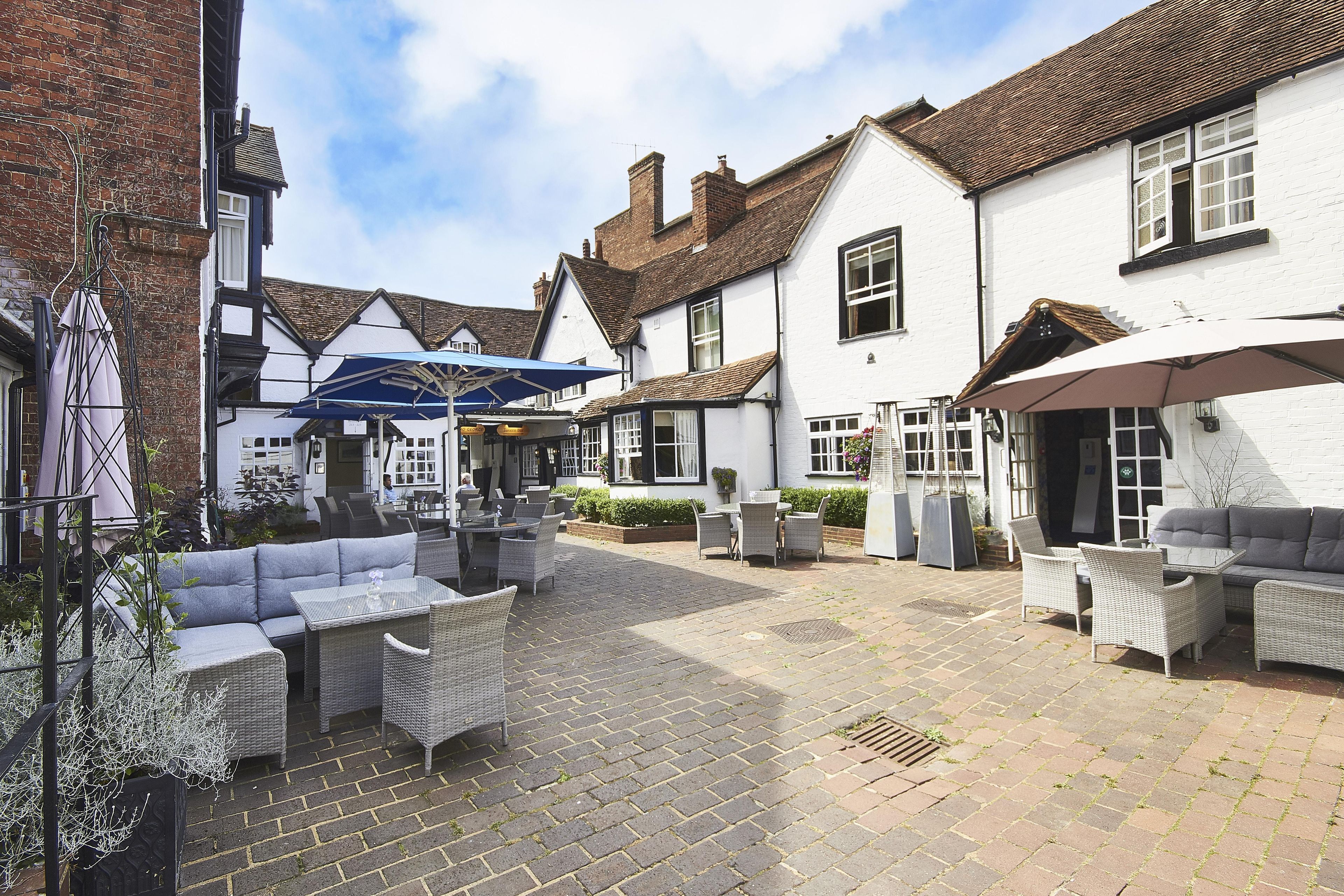 A courtyard with outdoor seating, a pub, and a white building with a traditional design.