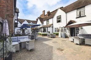 Een binnenplaats met terras, een pub en een wit gebouw met een klassiek ontwerp.