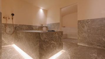 A modern bathroom with a marble vanity, a shower with a handheld showerhead, and a visible toilet.