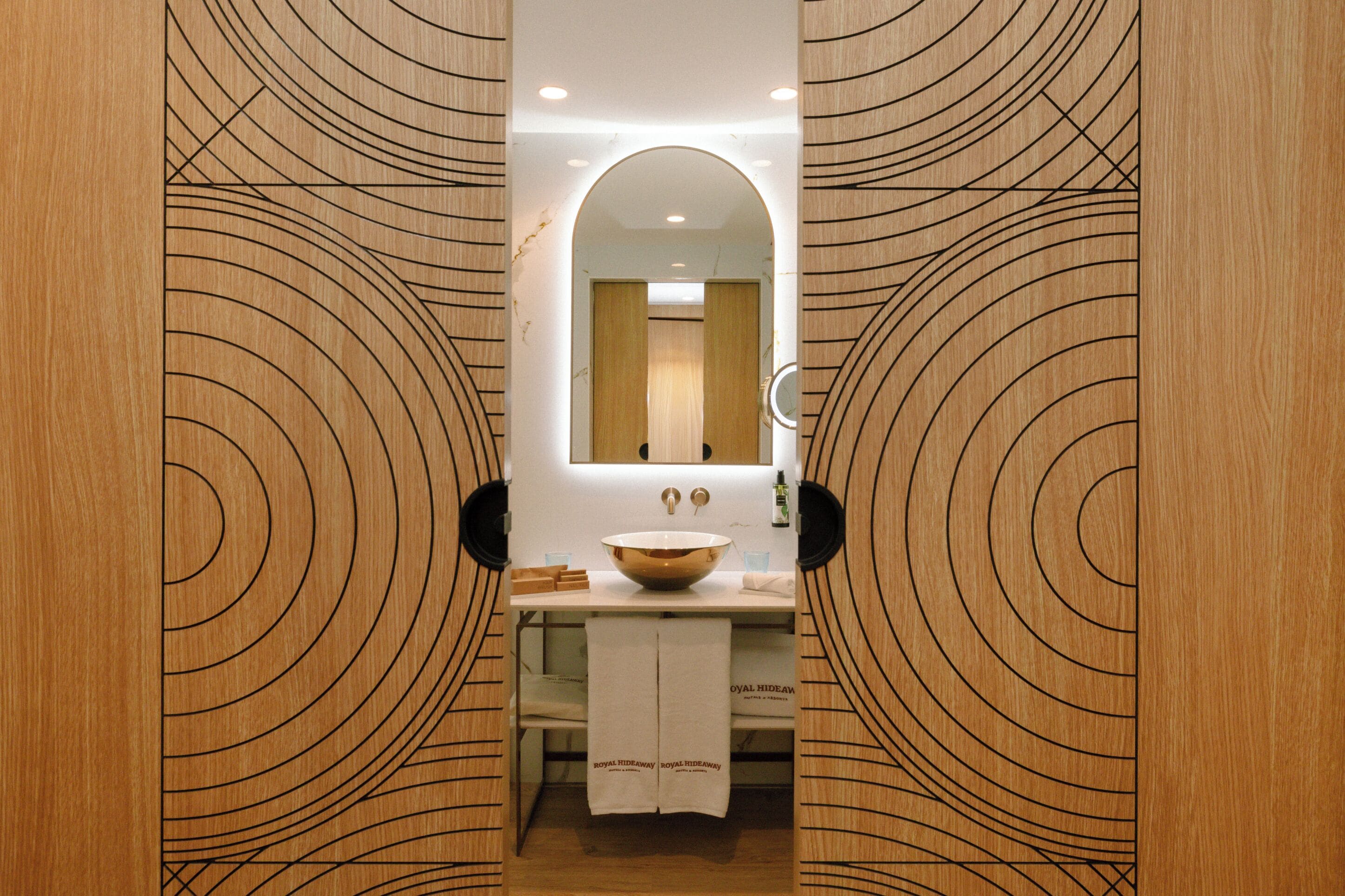 A bathroom with a wooden vanity, a large mirror, and a towel rack.