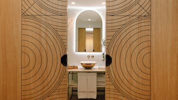 Une salle de bain avec un meuble-lavabo en bois, un grand miroir et un porte-serviettes.