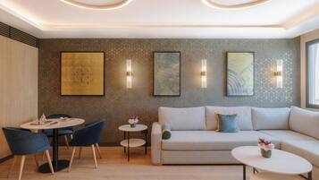 A modern living room with a sofa, two side tables, and a dining area with chairs and a small table.
