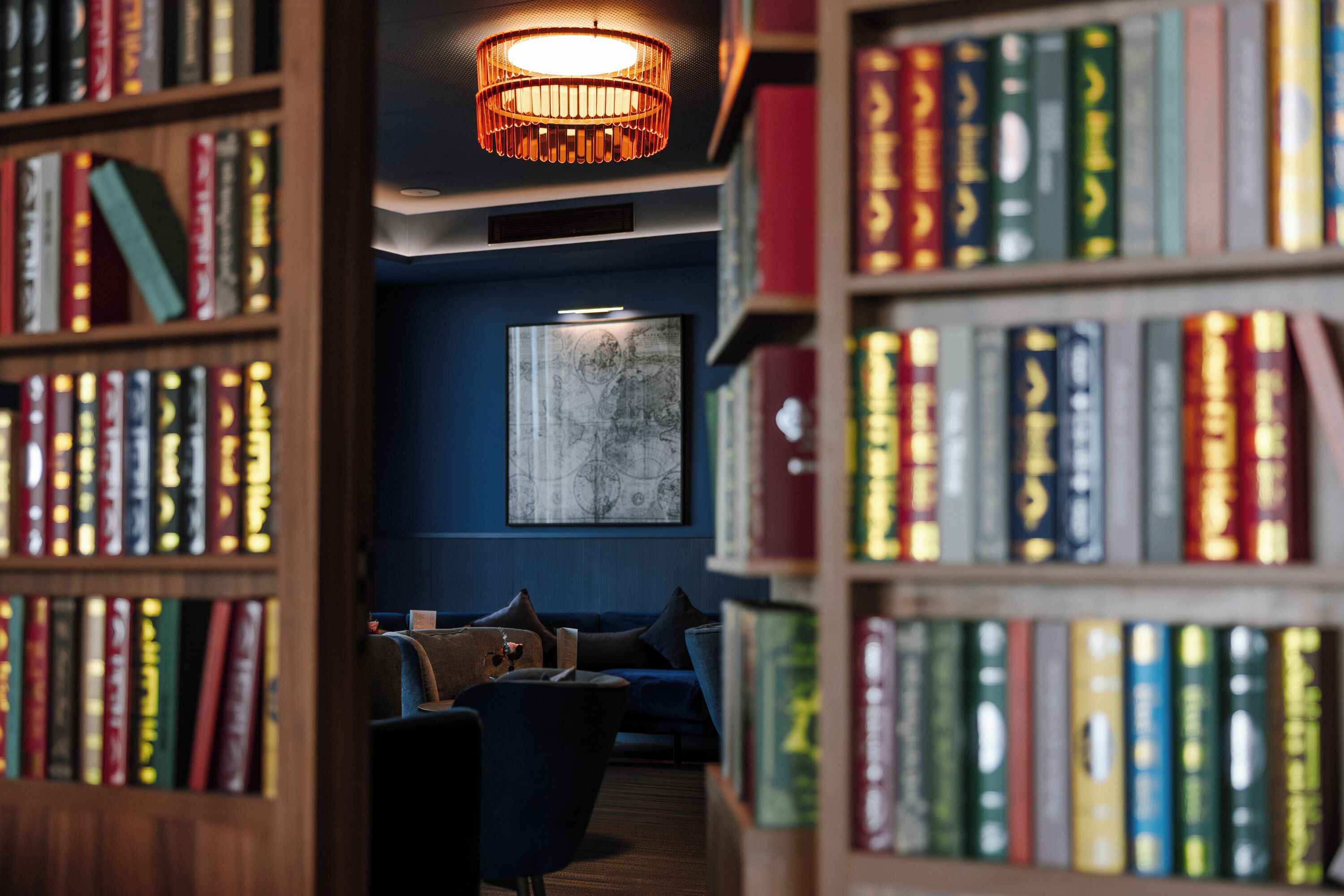 Een bibliotheek met boekenkasten, een bank en een hanglamp.