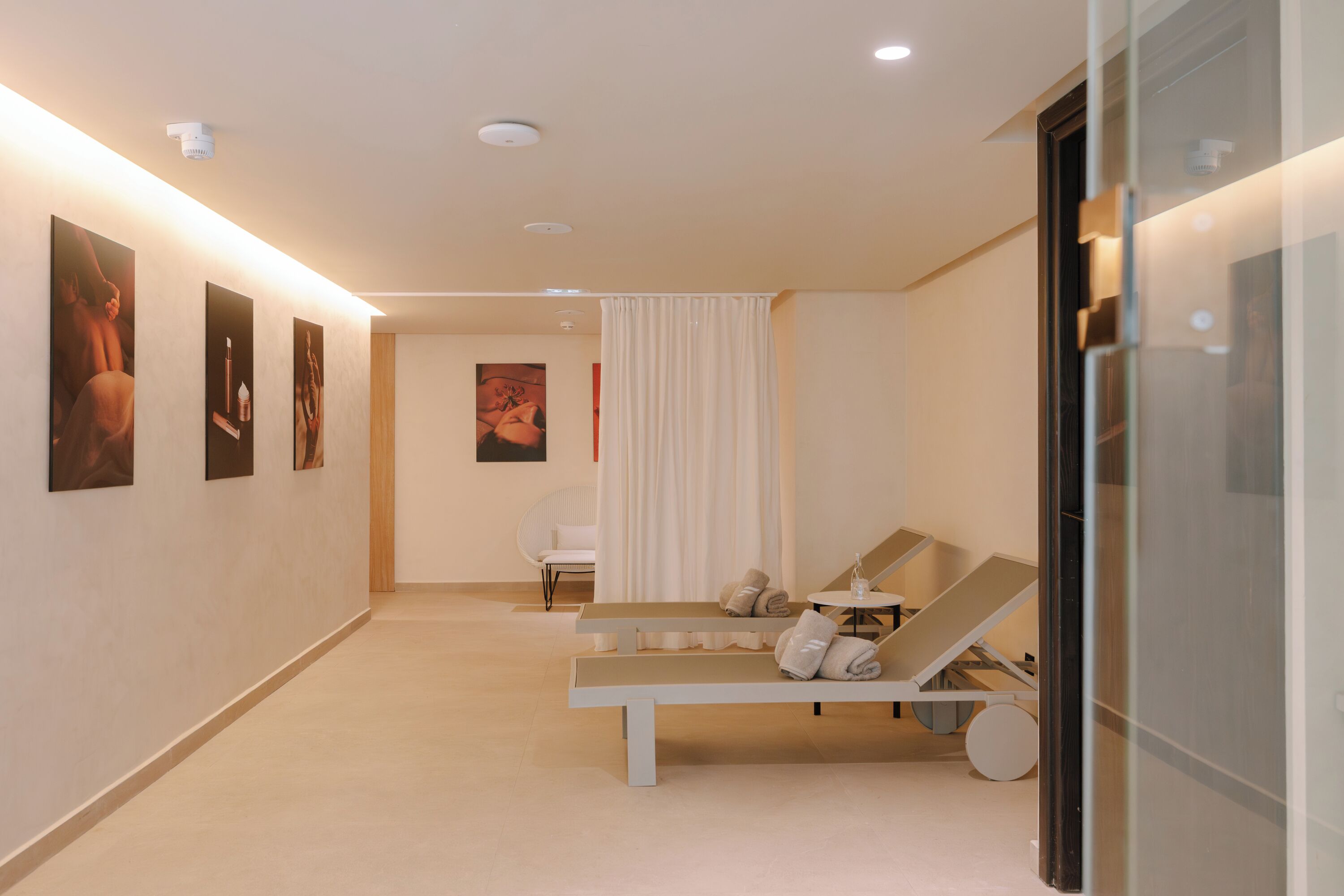 A modern spa room with a bench, a chair, and a small table with a glass.