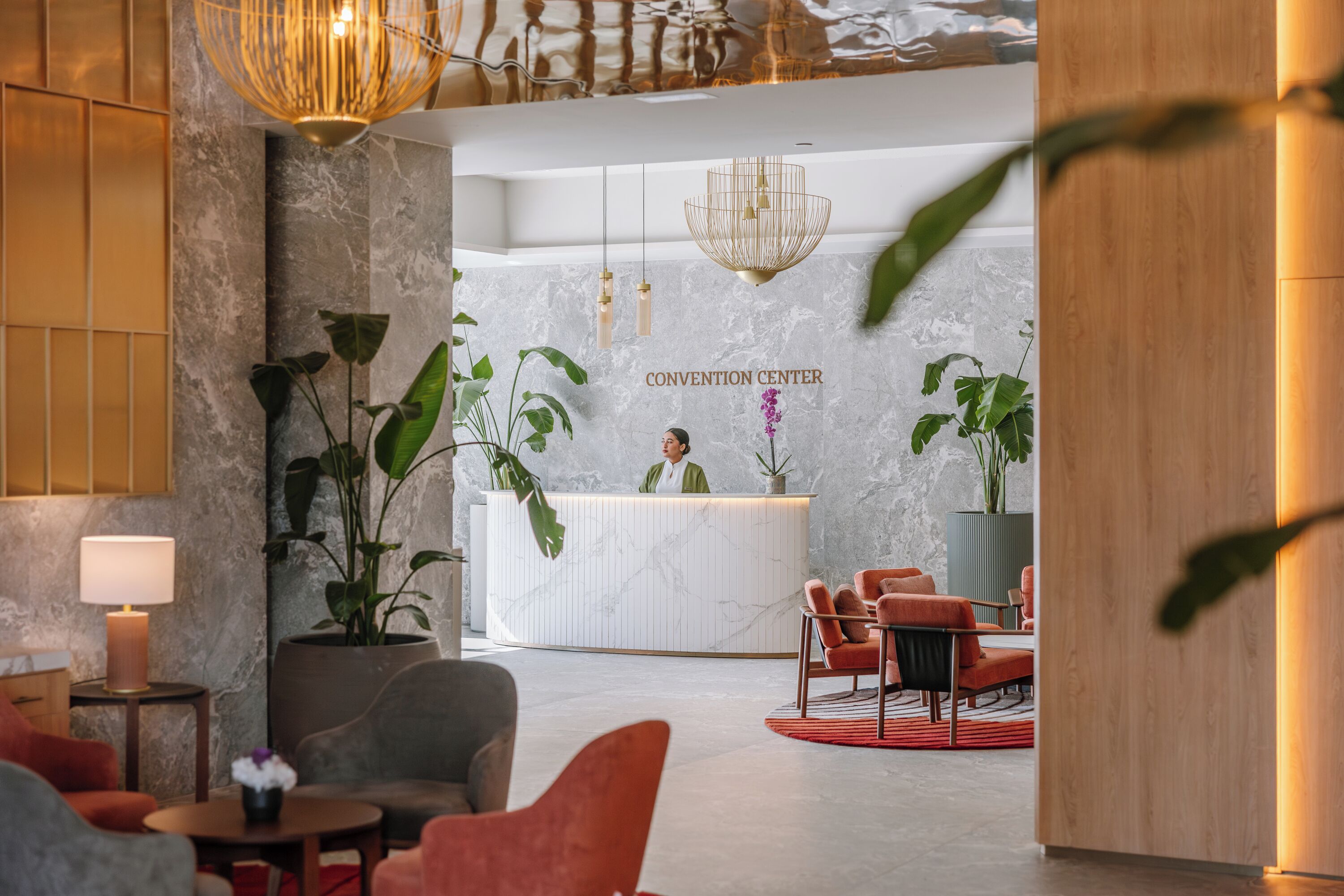 A reception area with a marble wall, a receptionist, and modern furniture.
