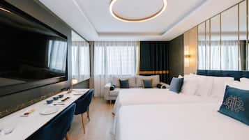 A modern hotel room with a large bed, a desk with a TV, and a sofa.
