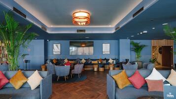 A modern lounge area with sofas, a large flat-screen TV, and a ceiling light fixture.