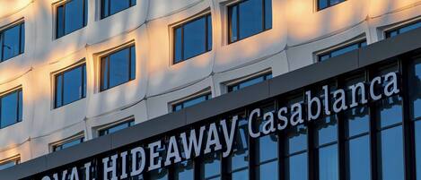 A building facade with a repeating pattern of windows and the text 'ROYAL HIDEAWAY Casablanca' indicating the hotel's name.