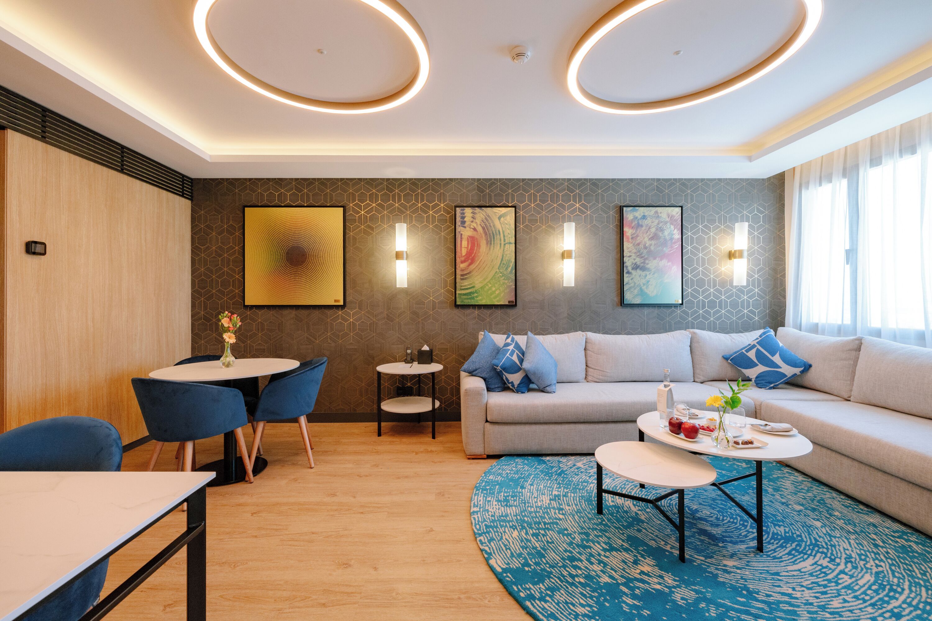 A modern living room with a sofa, two round tables, and a blue rug.