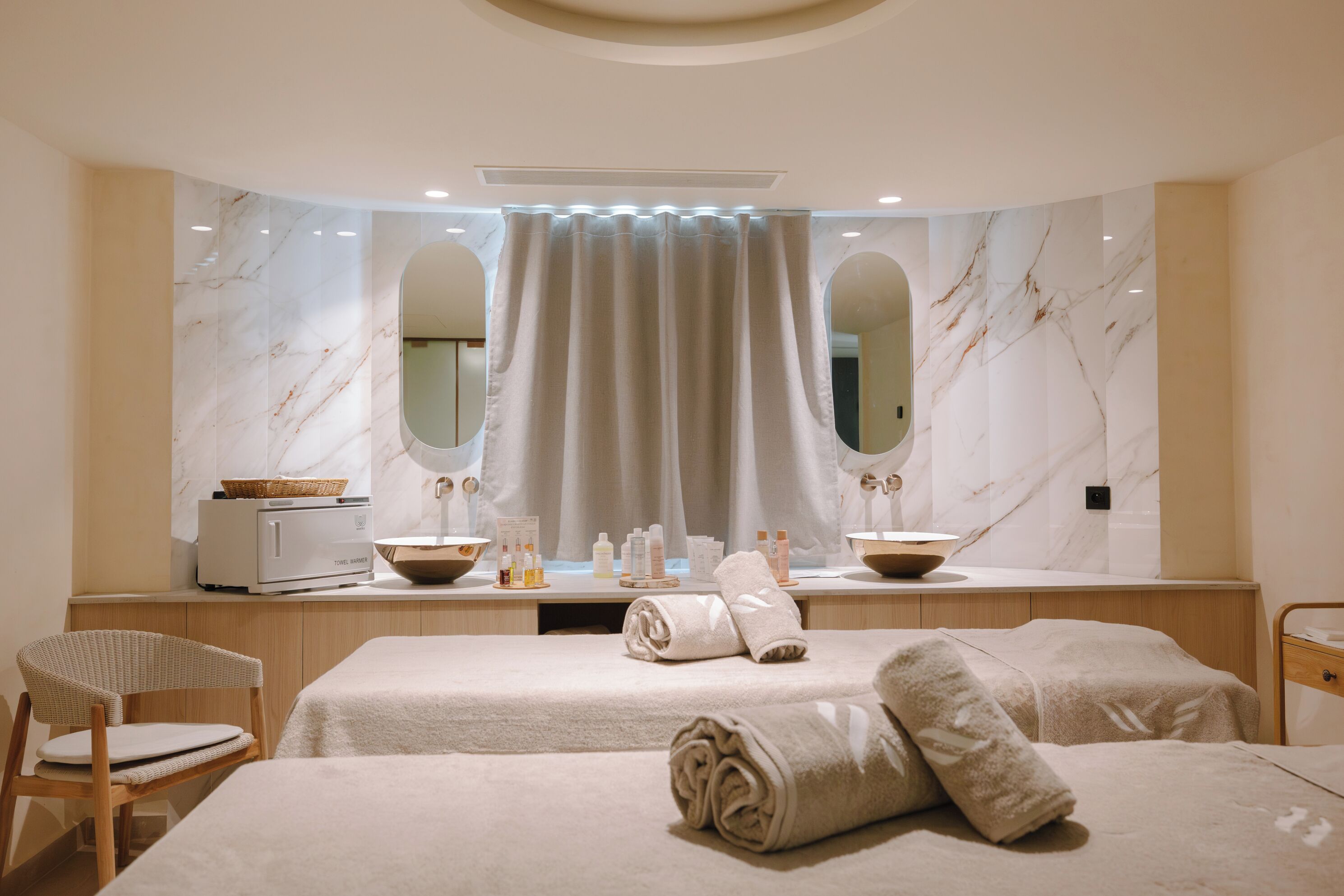 A hotel room with a large mirror, a vanity with a sink, and two beds with towels.