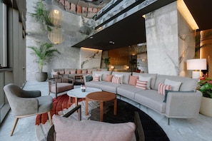 Un interior moderno con un sofá modular, una mesa de centro redonda y una zona de comedor con una mesa y sillas.