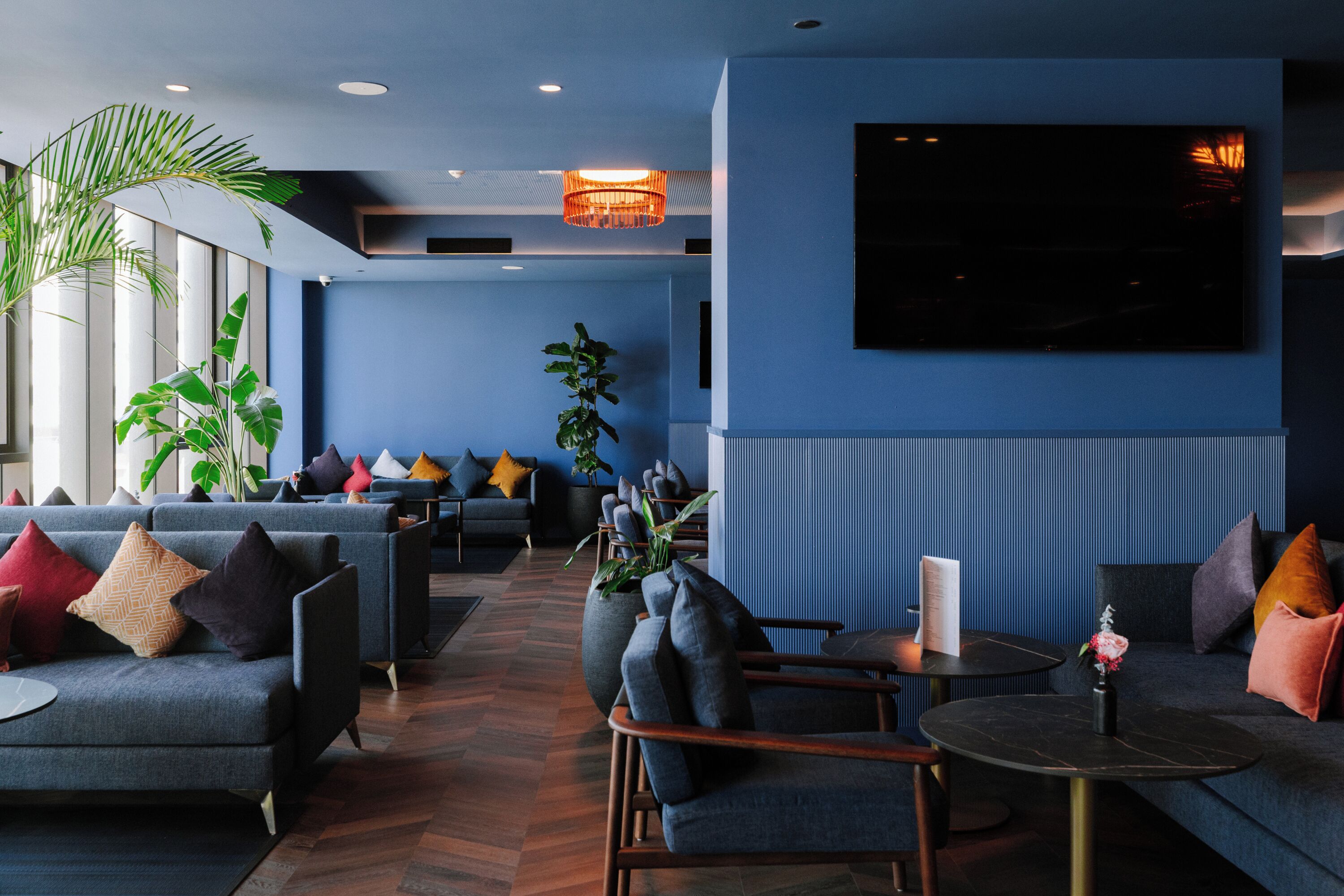 A modern lounge area with sofas, armchairs, a coffee table, and a TV mounted on the wall.