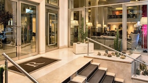 A hotel lobby with a reception desk, a staircase with a 'R' marking, and a glass railing overlooking the interior. - Renaissance Naples Hotel Mediterraneo (Naples)