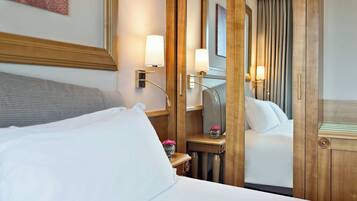 A hotel room with a bed, bedside tables, lamps, and a mirror.