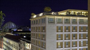 A multi-story hotel with a modern design, featuring balconies on the upper floors and a prominent dome structure in the background. - Renaissance Naples Hotel Mediterraneo (Naples)