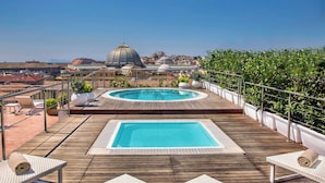 A rooftop pool area with a view of domed buildings in the background. - Renaissance Naples Hotel Mediterraneo (Naples)