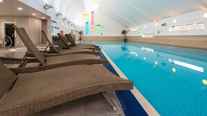 Une piscine dotée de chaises longues et d’un sol carrelé.