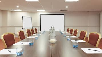 A conference room with a long table, chairs, a projector screen, and a whiteboard.