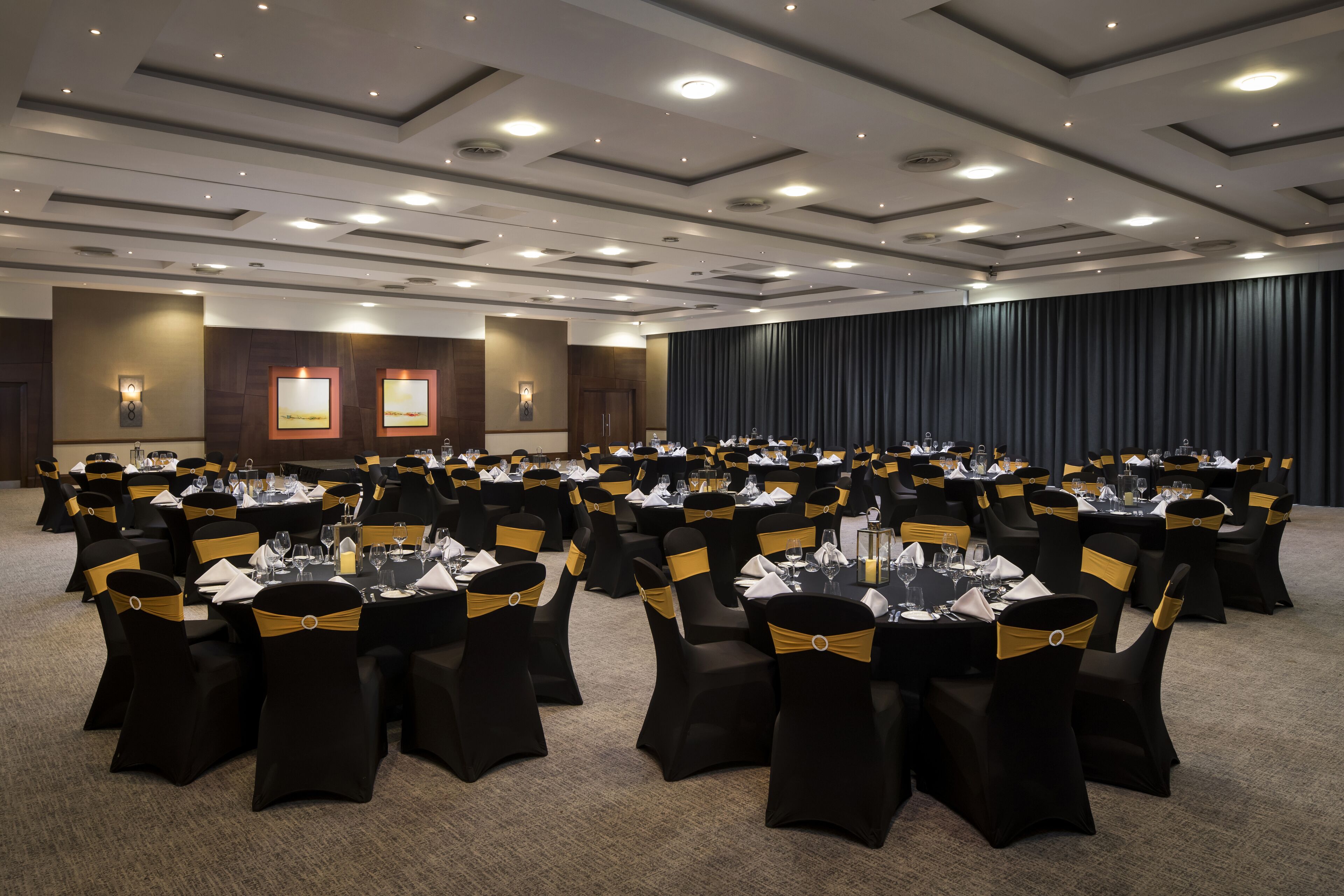 A large conference room with multiple round tables, each set with chairs and centerpieces.