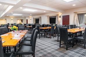 A conference room with multiple tables and chairs, a large screen, and a carpeted floor. - Britannia Aberdeen Hotel (Aberdeen)