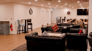 A hotel lobby with leather sofas, a bar area, a flat-screen TV, and a fireplace. - Britannia Aberdeen Hotel (Aberdeen)