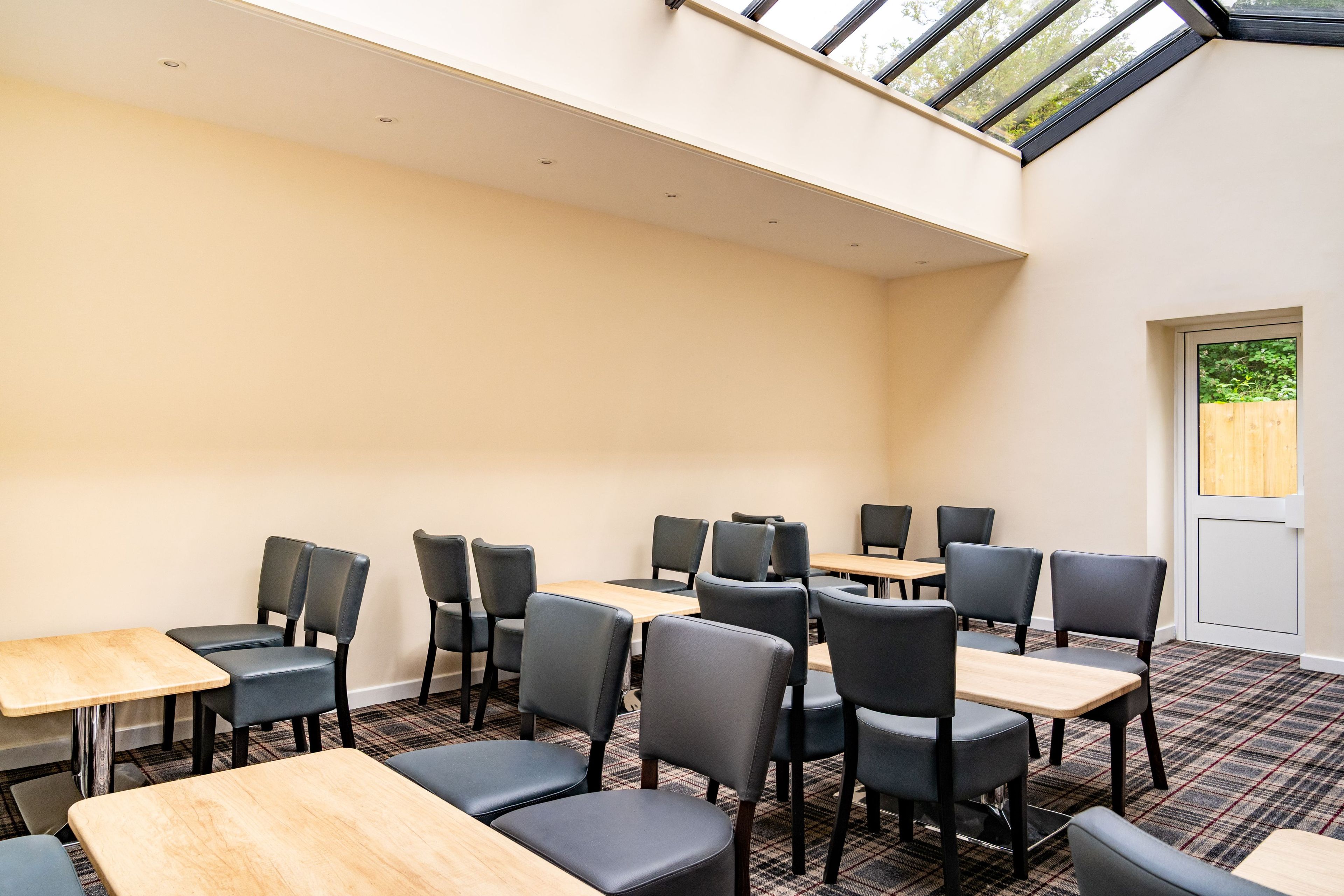 A conference room with tables and chairs, a high ceiling, and a skylight.