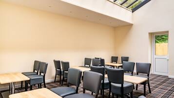 A conference room with tables and chairs, a high ceiling, and a skylight.