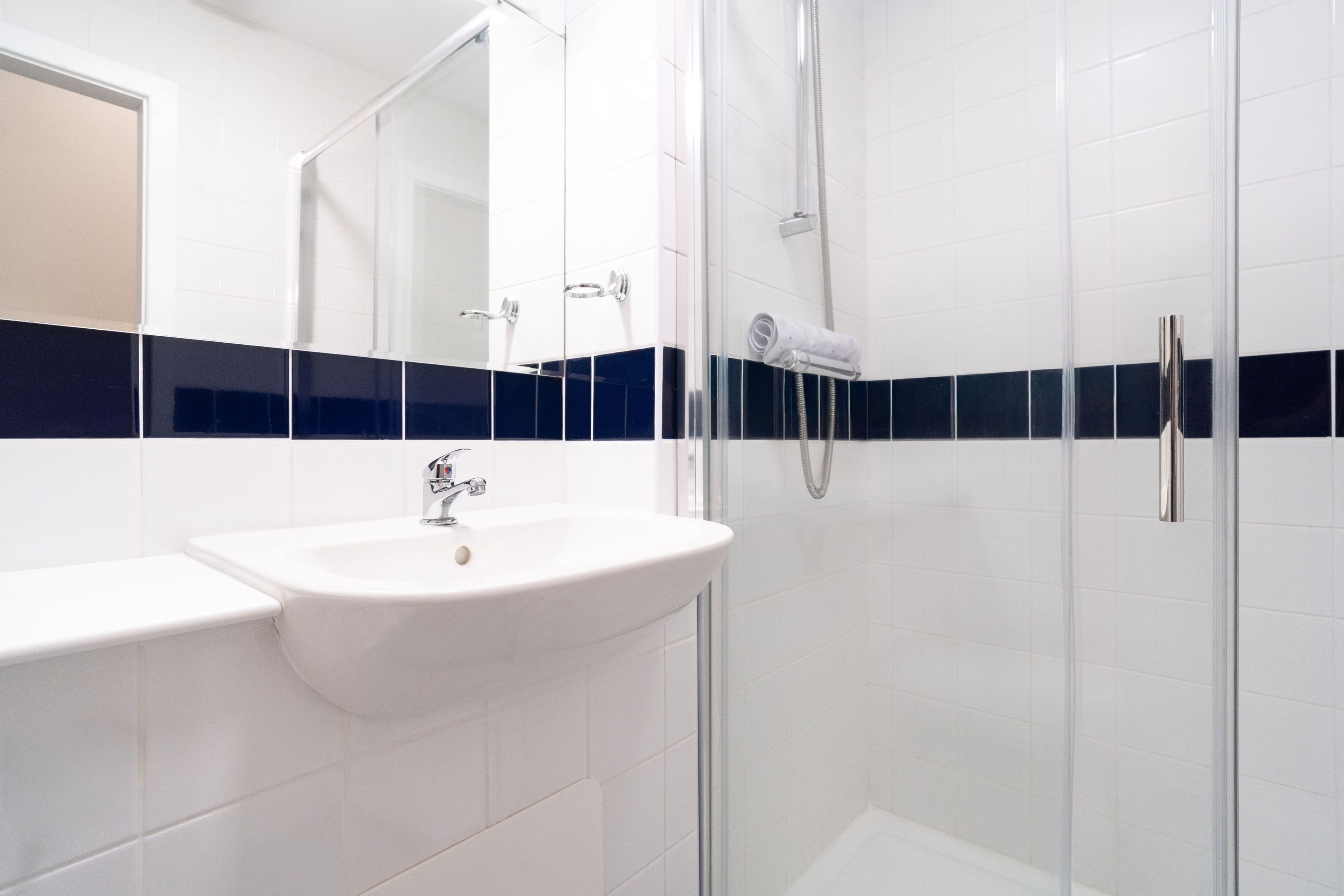 A modern bathroom with a glass shower enclosure, a white sink, and a mirror.