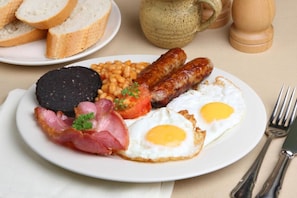 A plate of breakfast food including sausages, eggs, beans, and bacon.