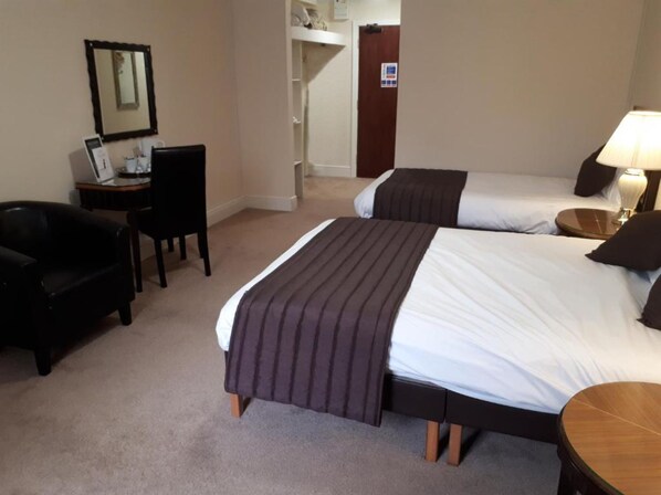 A hotel room with two beds, a desk, a chair, and a lamp. - Britannia Aberdeen Hotel (Aberdeen)
