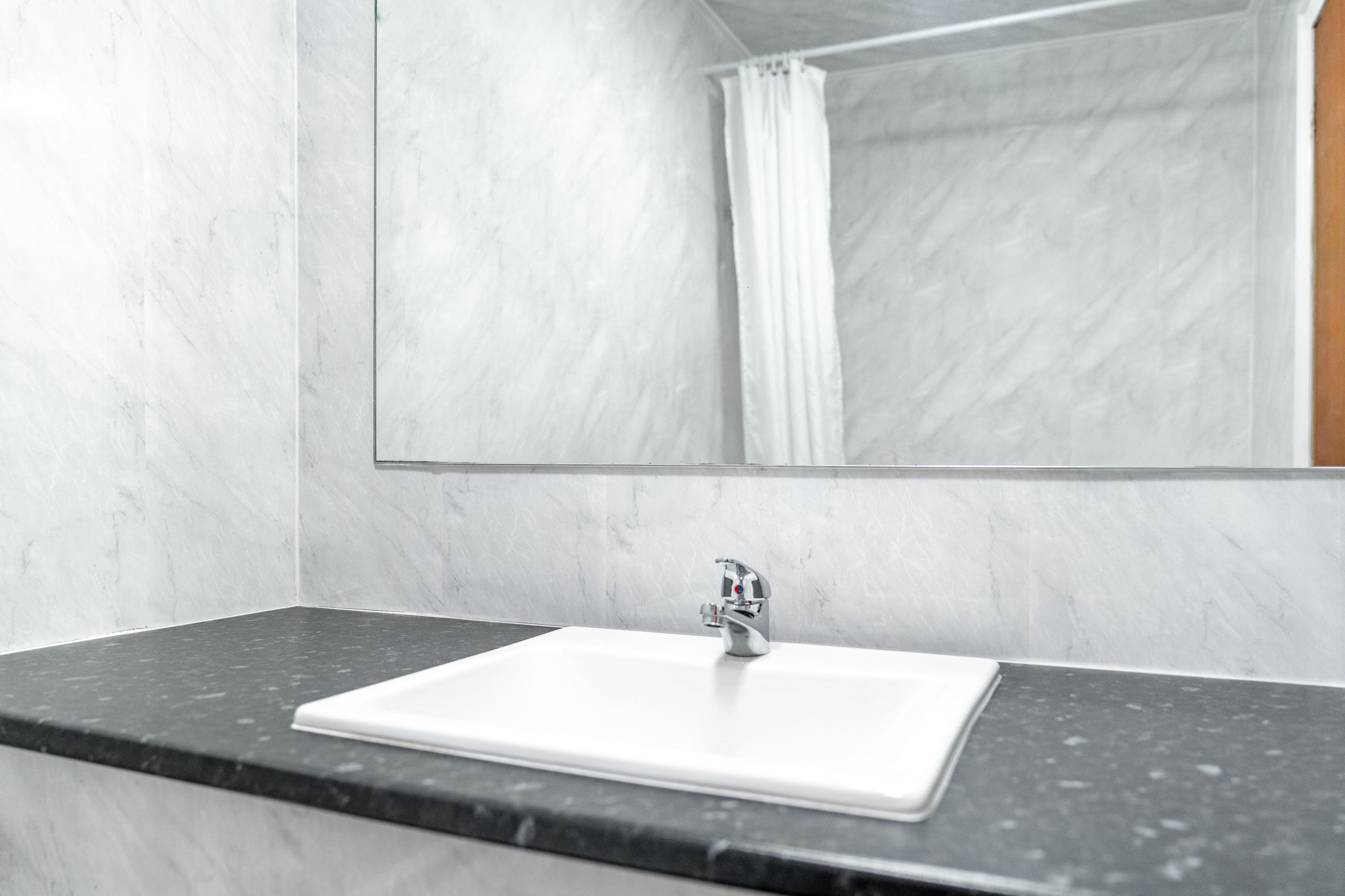 A bathroom with a white sink, a mirror, and a shower curtain.
