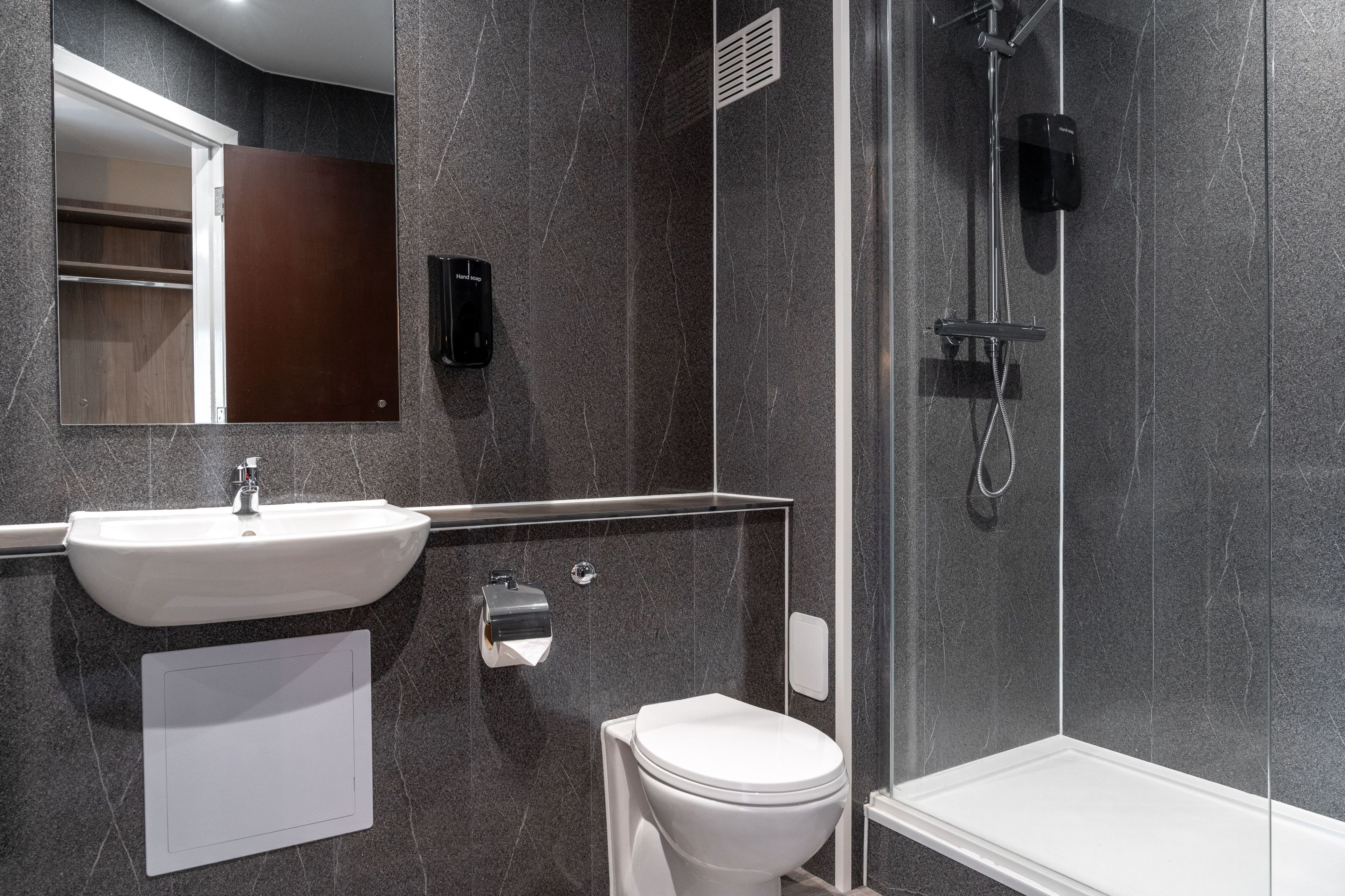 Un baño moderno con lavamanos blanco, inodoro y zona de ducha.