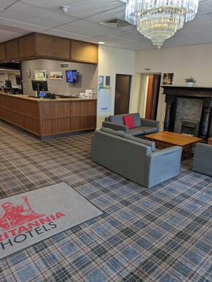 A lobby with a reception desk, seating area, and a fireplace. - Britannia Aberdeen Hotel (Aberdeen)