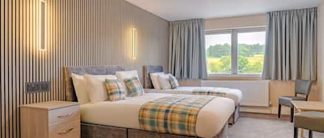 A hotel room with a large bed, bedside tables, a desk, and a view of the outdoors.