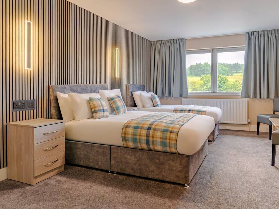 A hotel room with a large bed, bedside tables, a desk, and a view of the outdoors.
