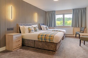 A hotel room with a large bed, bedside tables, a desk, and a view of the outdoors. - Britannia Aberdeen Hotel (Aberdeen)