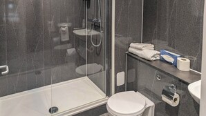 A modern bathroom with a glass-enclosed shower, a toilet, a sink, and a towel rack.