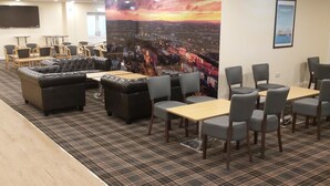 A conference room with a cityscape mural, a large black sofa, and several tables and chairs. - Britannia Aberdeen Hotel (Aberdeen)