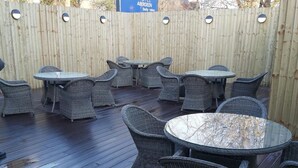 An outdoor patio area with wicker furniture and a sign for Britannia Hotel Aberdeen. - Britannia Aberdeen Hotel (Aberdeen)
