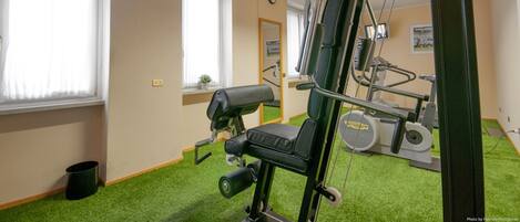 A gym with exercise equipment, a mirror, and a clock on the wall.