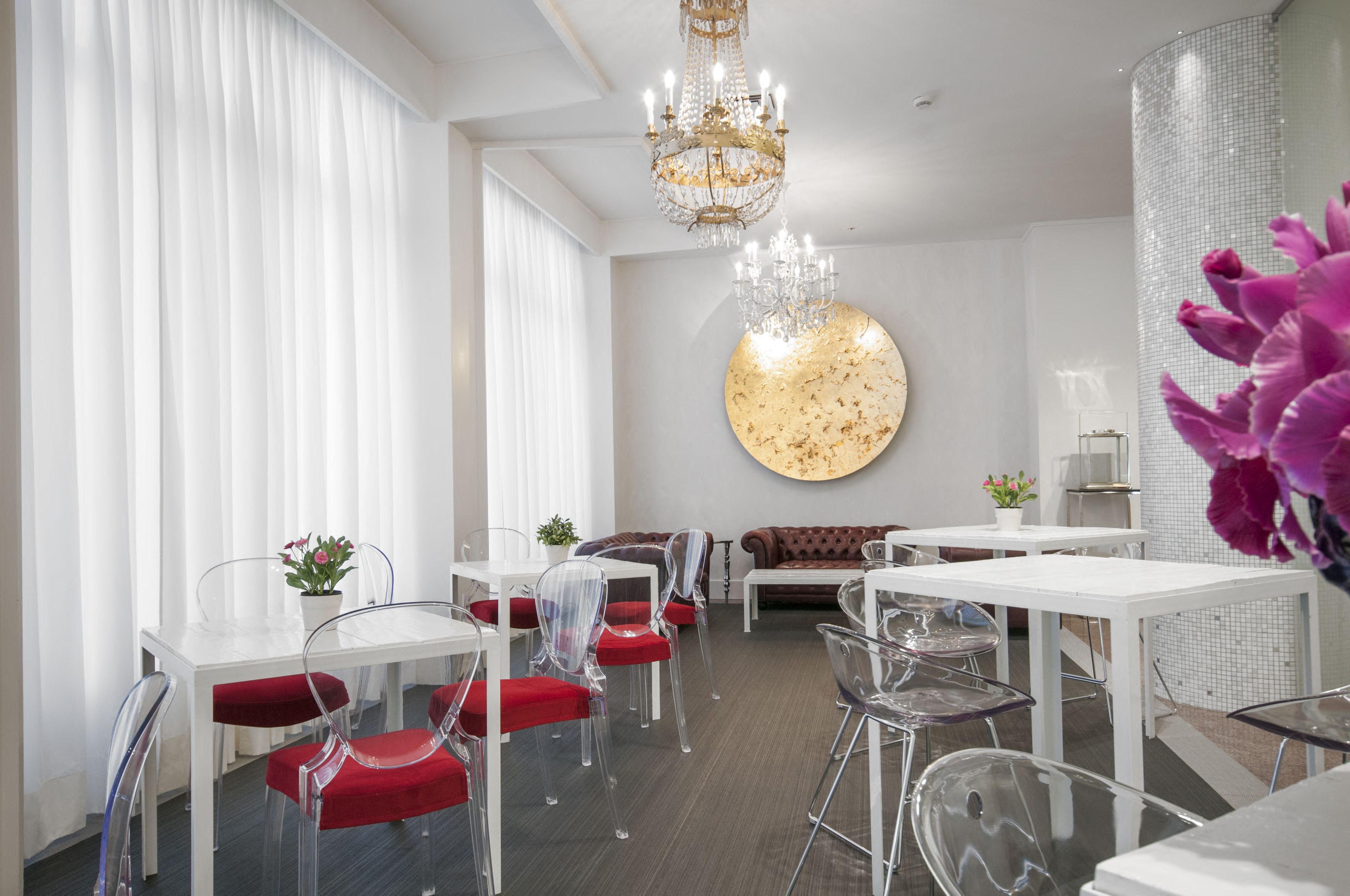 A modern dining area with clear chairs, a white table, and a chandelier.
