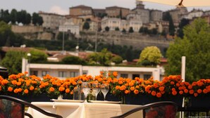 A table set with wine glasses and a view of historic buildings in the background. - Hotel Excelsior San Marco (Bergamo)