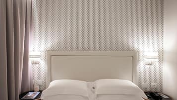Een hotelkamer met een net opgemaakt bed, een nachtkastje met een lamp en een muur met behang.