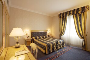 A hotel room with a large bed, two bedside tables with lamps, a mirror, and a view of the outdoors through curtains.